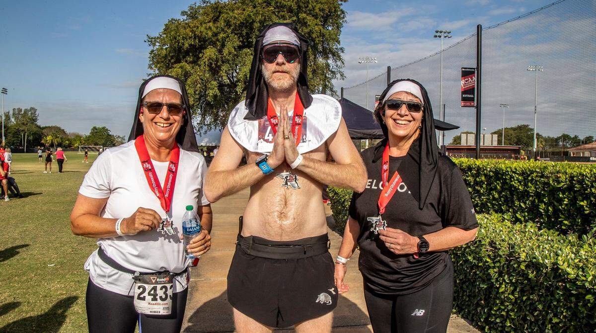 Runners Lisa Spinosa and Lisa Mercado, of Miami, posed with Tom Lefner, of Ohio, after he won the Barry University 8K Nun Run on Saturday April 9, 2022.