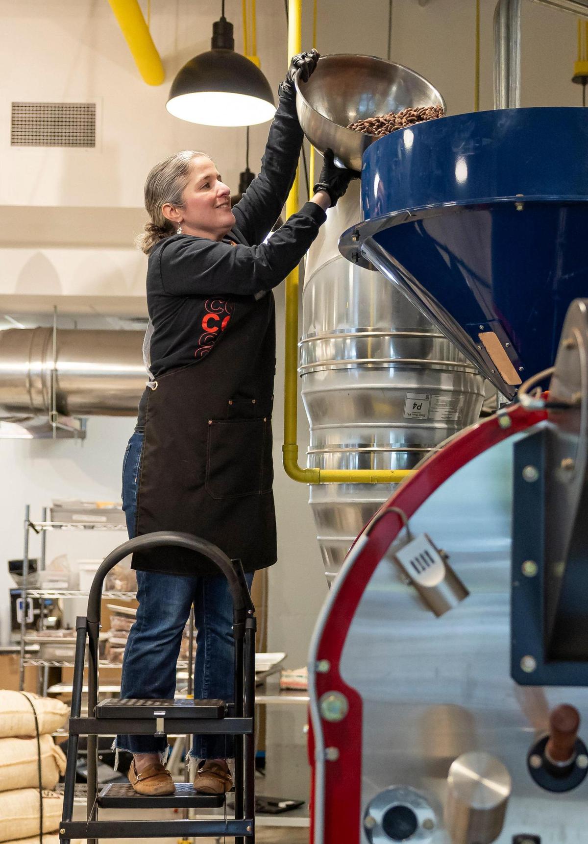 Carolina Quijano, founder of Exquisito Chocolates, loads cacao beans into a repurposed coffee roaster at her new factory.