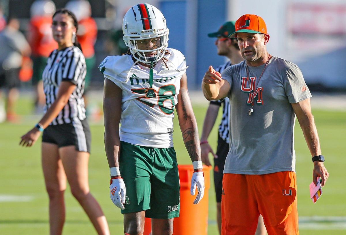 Miami Hurricanes head coach Manny Diaz talks with cornerback Marcus Clarke (28) as the University of Miami opens 2021 fall camp on Friday night in Coral Gables on Friday, August 6, 2021.