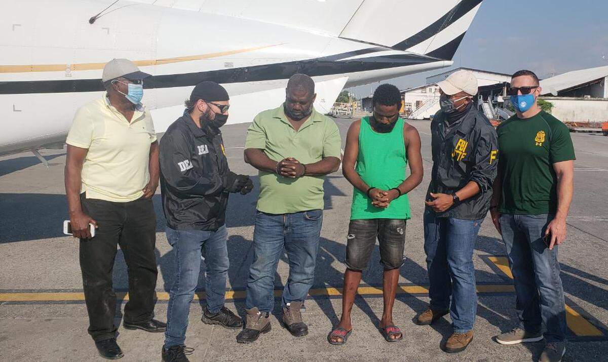 Federal agents with the Federal Bureau of Investigations and Drug Enforcement Administration arrived in Haiti Friday, March 5, 2021 to fly out two individuals. Lissner Mathieu, 55, in the light green shirt, is a U.S. fugitive known as “Ti-Nwa.” Next to him, in a a dark green shirt, is Peterson “Ti Peter Vilaj” Benjamin (right), a Haitian national. Both men were arrested earlier in the week by Haiti National Police.