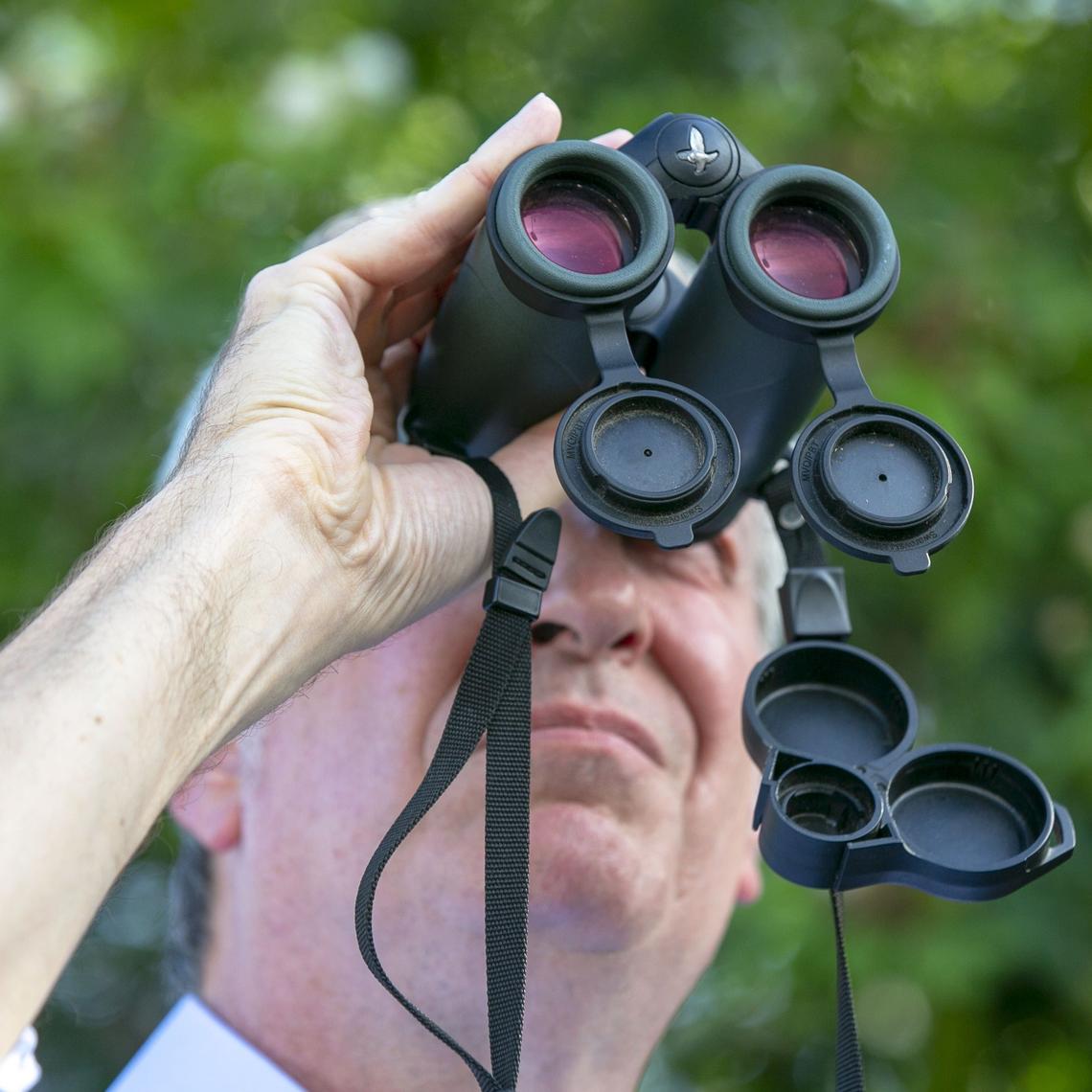 Democratic presidential candidate Bill de Blasio uses binoculars as he tries to spot the migrant children across the road during a visit to the Homestead detention center on June 27, 2019.