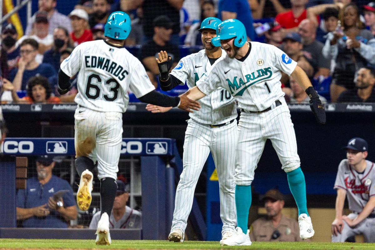 Miami Marlins base runner Xavier Edwards (63) reacts at home plate with teammates Yuli Gurriel (10) and Garrett Hampson (1) after the trio scored off a Jacob Stallings (58) double during the seventh inning of an MLB game against the Atlanta Braves at loanDepot park in the Little Havana neighborhood of Miami, Florida, on Friday, September 15, 2023