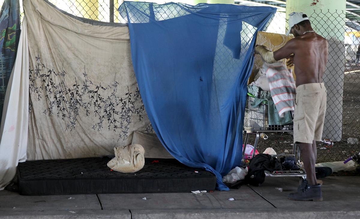 Willie Ward, a homeless man, packs his belongings as a cleaning brigade swept the streets under the 836/Dolphin Expressway early Friday.