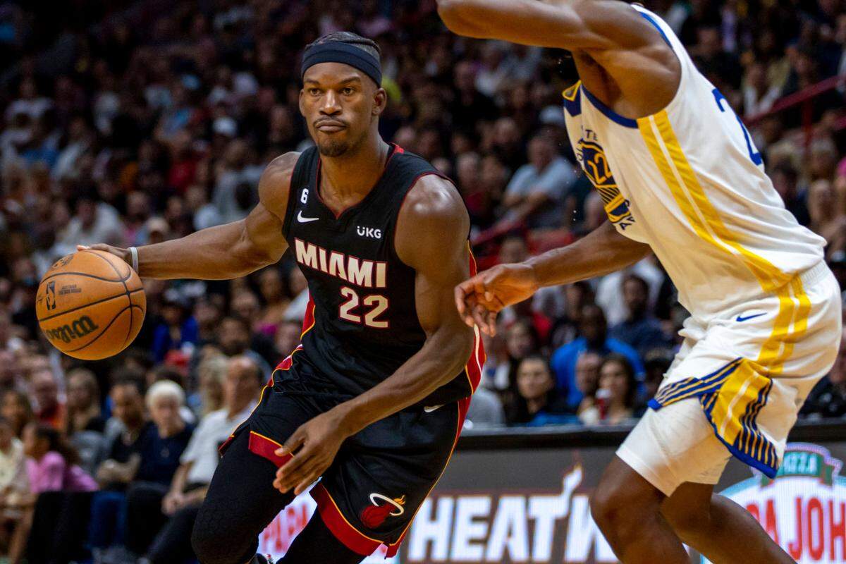 Miami Heat forward Jimmy Butler (22) drives toward the paint while defended by Golden State Warriors forward Andrew Wiggins (22) during the first half of an NBA game at FTX Arena in Downtown Miami, Florida, on Tuesday, November 1, 2022.