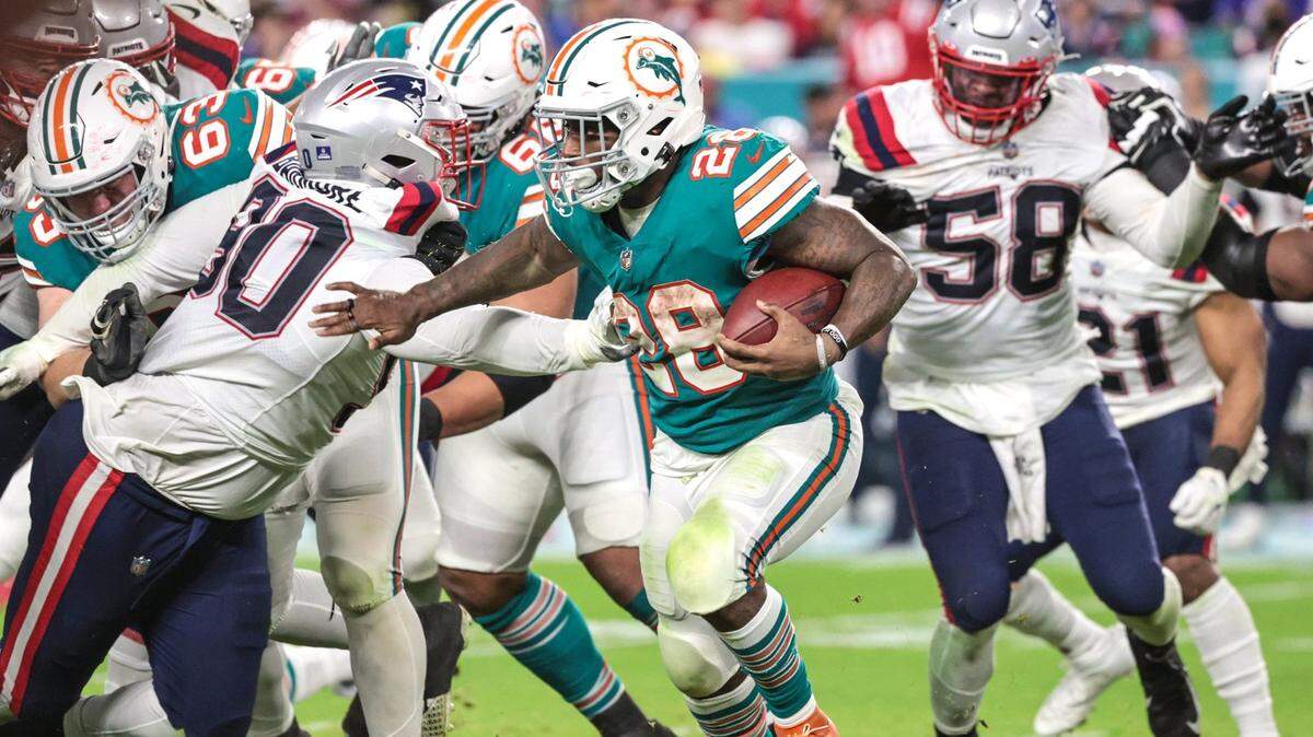 Miami Dolphins running back Duke Johnson (28) battles through the line of scrimmage in the fourth quarter against the New England Patriots in the at Hard Rock Stadium in Miami Gardens on Sunday, January 9, 2022.