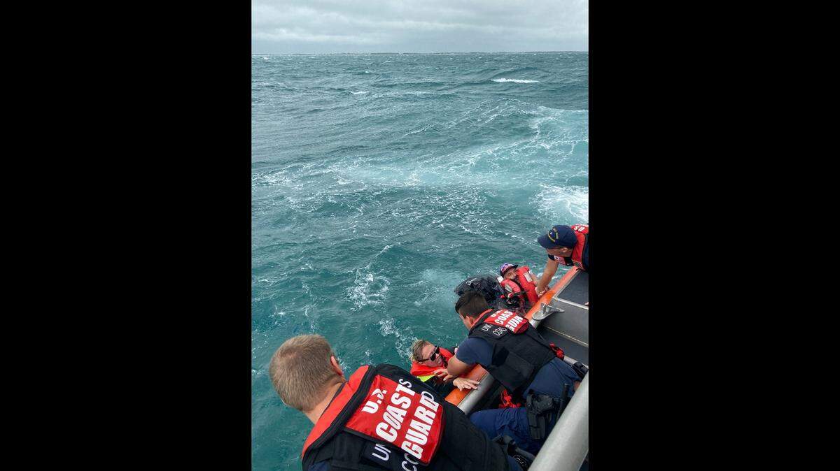 A Coast Guard Station Islamorada 45-foot Response Boat—Medium boatcrew start to pull a woman and a man aboard the station boat because their vessel began taking on water in the vicinity of Windley Island, Florida, Nov. 9, 2019.