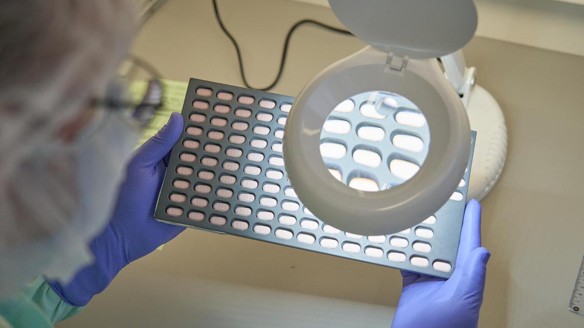 In this photo provided by Pfizer, a lab technician visually inspects Paxlovid tablet samples in Freiburg, Germany, in December 2021. Studies showed that the first pill to treat the virus led to a nearly 90% reduction in hospitalizations and deaths among patients most likely to get severe disease. The pill is being rolled out in Florida and across the nation. (Pfizer via AP)