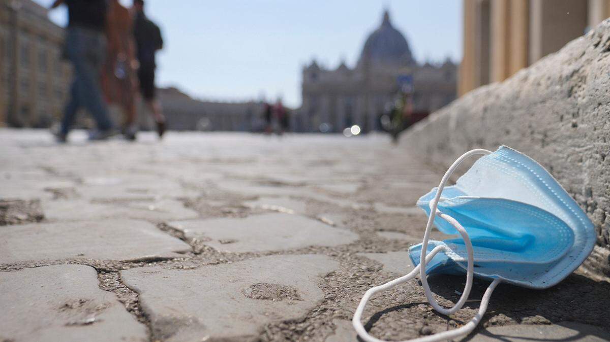 A protective mask is seen on the ground near St. Peter’s Square, in Rome on Aug. 12, 2020. Researchers at Washington State University say fibers from used masks could help make concrete more durable.