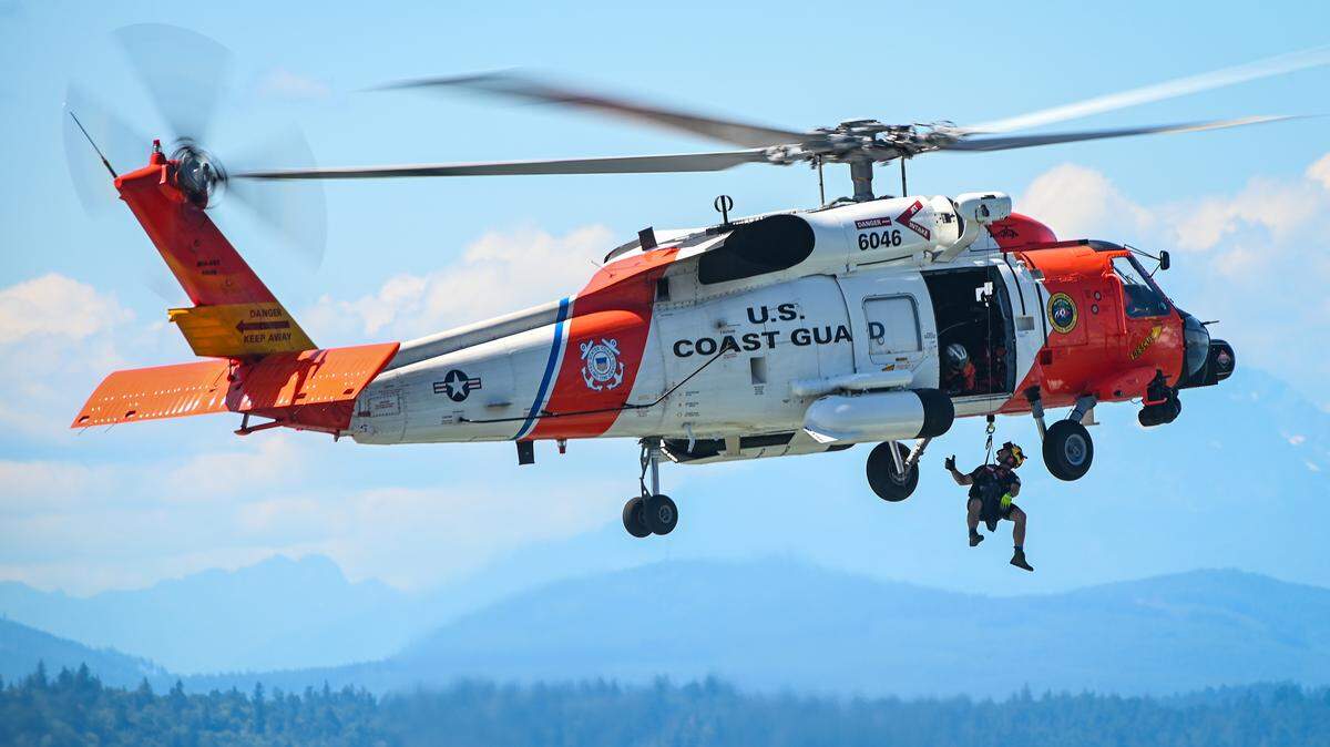 A rescue swimmer from U.S. Coast Guard Air Station Astoria dangles below an MH-60 Jayhawk helicopter as it hovers above Elliott Bay near Seattle, Washington, Aug. 1, 2023. A similar helicopter based at Air Station Clearwater took part in a search for a woman who went overboard from a cruise ship off Cuba Thursday, Jan. 1, 2026.