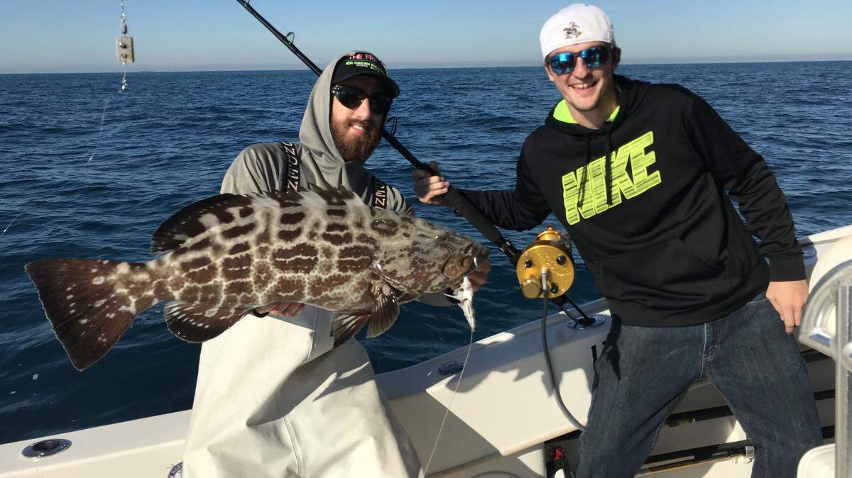 Mate Abie Raymond, left, of Bouncer’s Dusky 33 holds a big black grouper that Kyle Whyte caught trolling skirted ballyhoo along a reef in 26 feet of water south of Fowey Light.