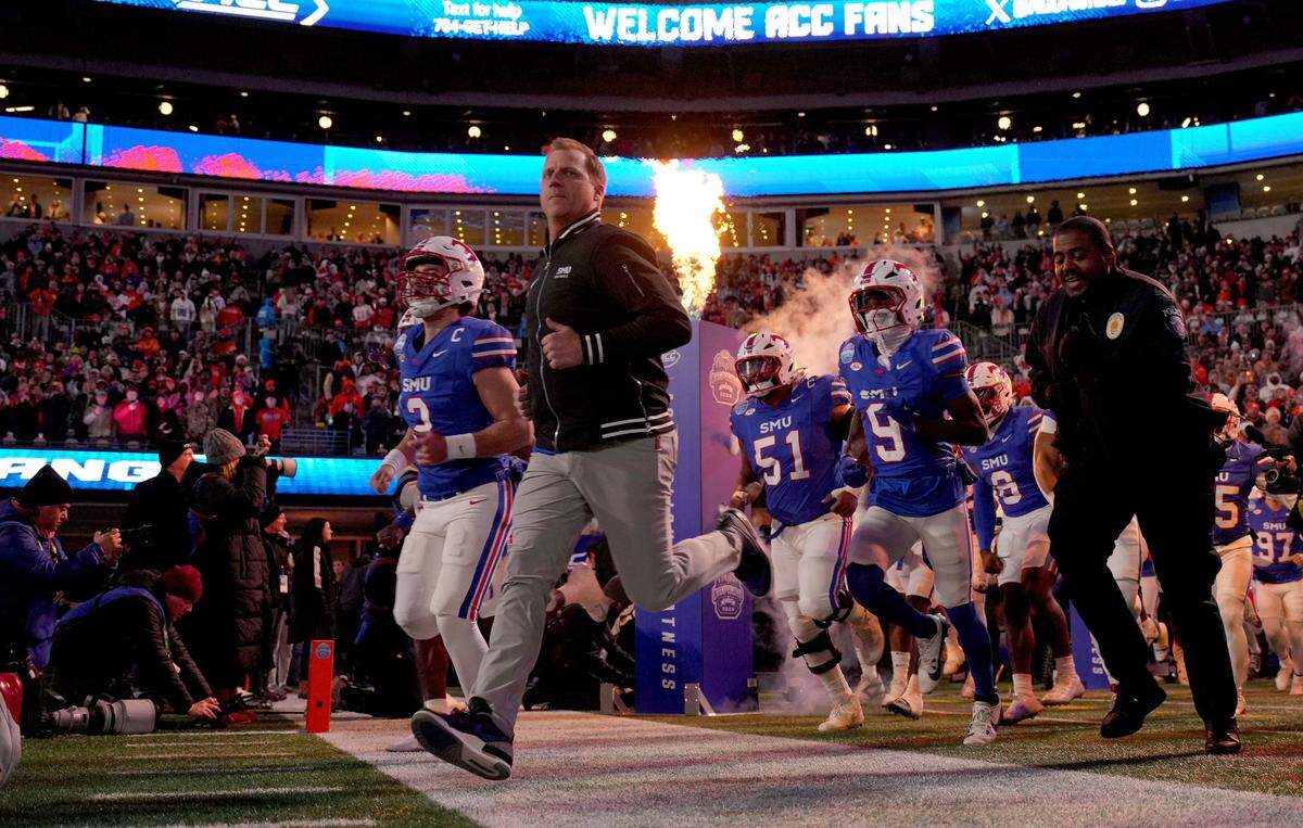 Dec 7, 2024; Charlotte, NC, USA; Southern Methodist Mustangs head coach Rhett Lashlee leads his team to the field before the 2024 ACC Championship game against the Clemson Tigers at Bank of America Stadium.
