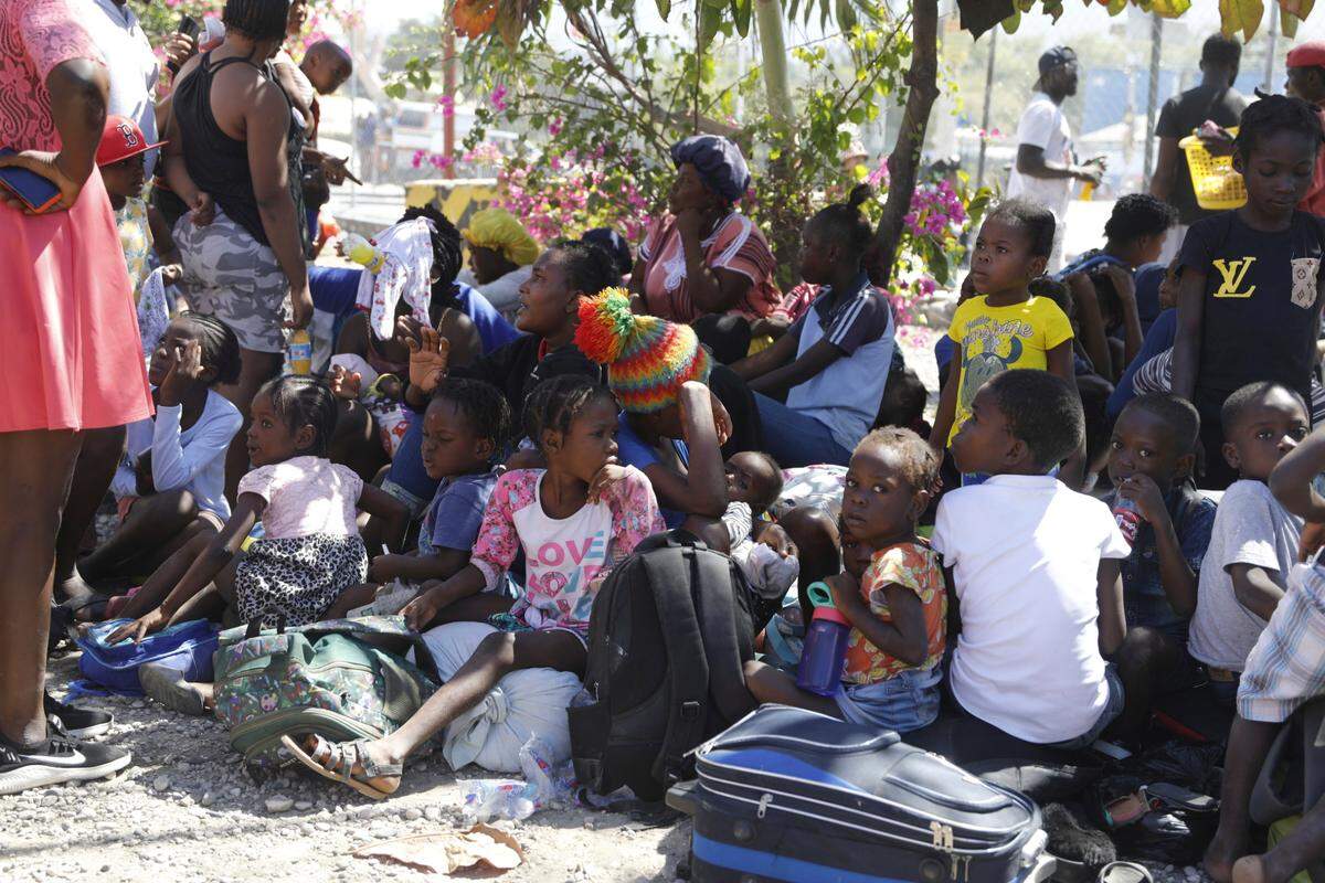 Children and their guardians gather outside a police station after they fled their homes in Cite Soleil due to gang violence, in Port-au-Prince, Haiti, Monday, Feb. 12, 2024. (AP Photo/Odelyn Joseph)