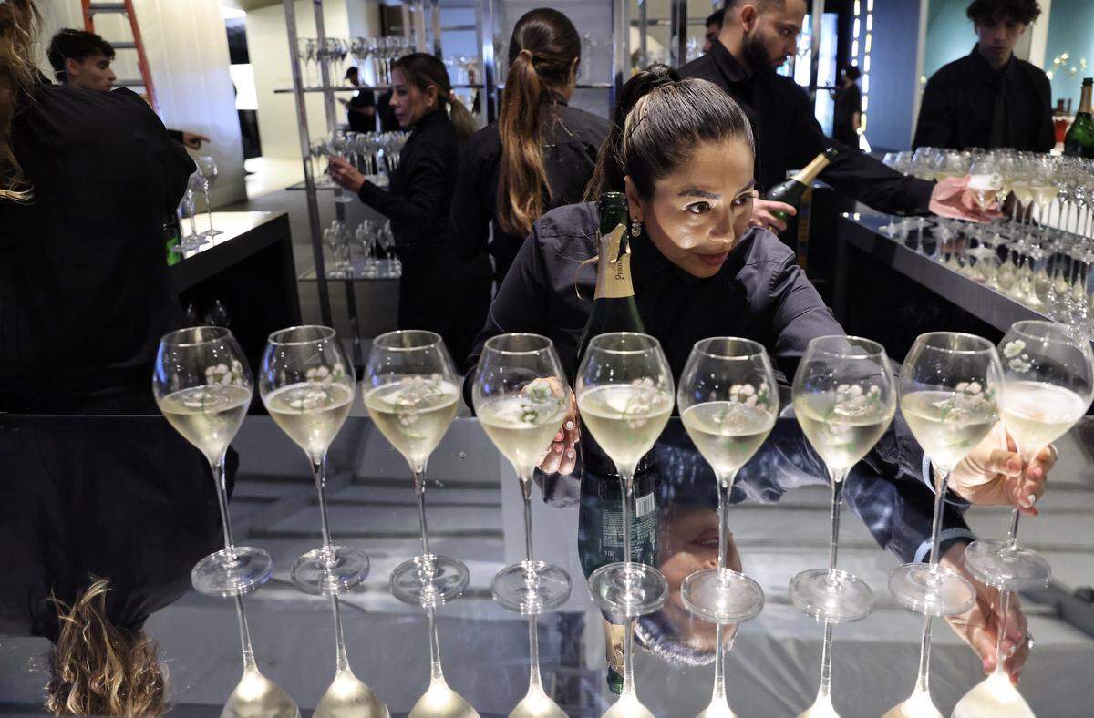 Miami Beach, FL, December 2, 2025 -  A server fills glasses of Perrier-Jouët champagne as Design Miami XX opens its doors during Miami Art Week