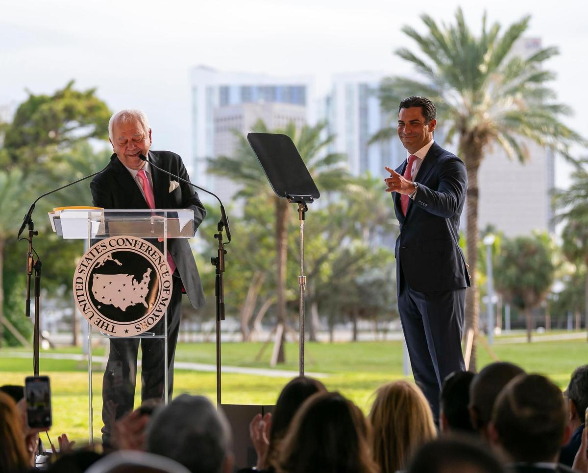 Miami Mayor Francis Suarez, right, reacts as CEO and Executive Director of the United States Conference of Mayors Tom Cochran speaks during Suarez’s inauguration ceremony as the 80th president of the U.S. Conference of Mayors at Maurice A. Ferré Park in downtown Miami on Monday, Jan. 3, 2022. The conference brings together municipal leaders from across the country to discuss issues facing local governments.