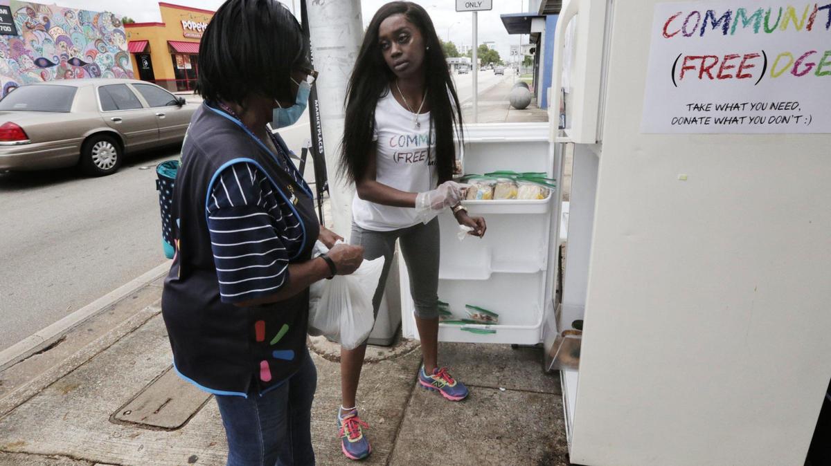 Sherina Jones, center, passes out food from the community refrigerator she set up to feed locals who may be struggling due to the pandemic.