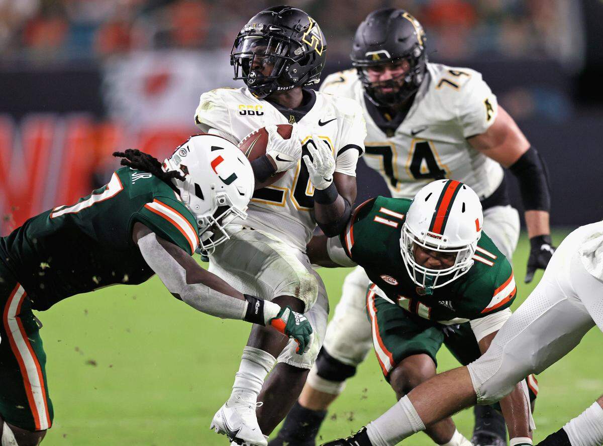 Miami Hurricanes linebacker Waynmon Steed (17) and Hurricanes linebacker Corey Flagg Jr. (11) tackle Appalachian State Mountaineers running back Nate Noel (20) during the third quarter of their ACC football game at Hard Rock Stadium on Saturday, September 11, 2021 in Miami Gardens, Florida.