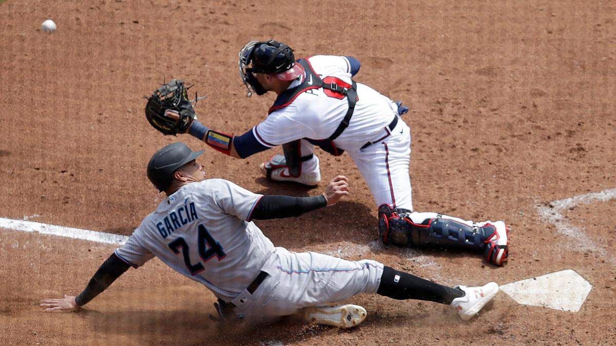 Miami Marlins’ Avisail Garcia (24) scores as Atlanta Braves catcher Manny Pina (9) waits for the ball in the fifth inning of a baseball game Sunday, April 24, 2022, in Atlanta. Garcia scored on a single by Marlins’ Garrett Cooper. (AP Photo/Ben Margot)