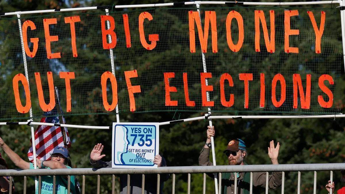 In 2016, supporters of a Washington state initiative to tamp down on big-money campaign donors hold a sign over a freeway. 