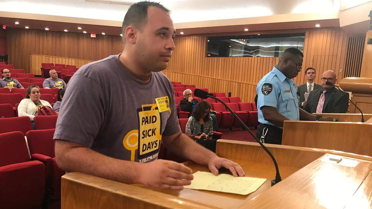 Joshua Lee Bleicher, a Metrorail guard, addresses Miami-Dade commissioners on Thursday, Feb. 13, 2020, about a bill that would require county contractors to provide workers like him paid sick time, family leave and parental leave. At the other lectern, airport guard Roosvelt Derameau waits his turn to speak.