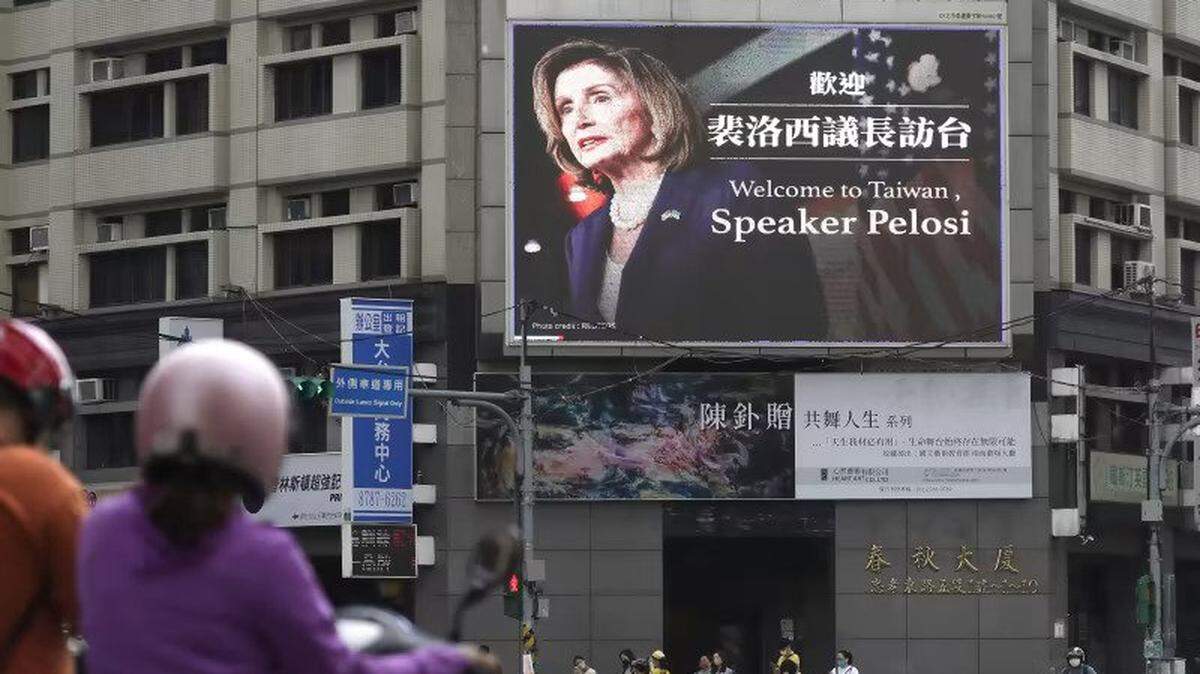 People walk past a billboard welcoming U.S. House Speaker Nancy Pelosi, in Taipei, Taiwan on Aug 3.