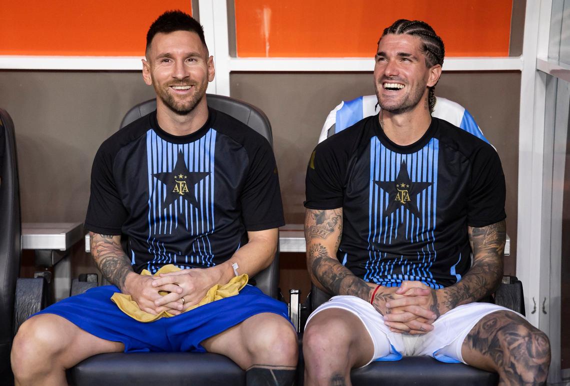 Argentina forward Lionel Messi (10) and midfielder Rodrigo De Paul (7) look on from the bench before the start of his CONMEBOL Copa America 2024 group A soccer match against Peru at Hard Rock Stadium on Saturday, June 29, 2024, in Miami Gardens, Fla.