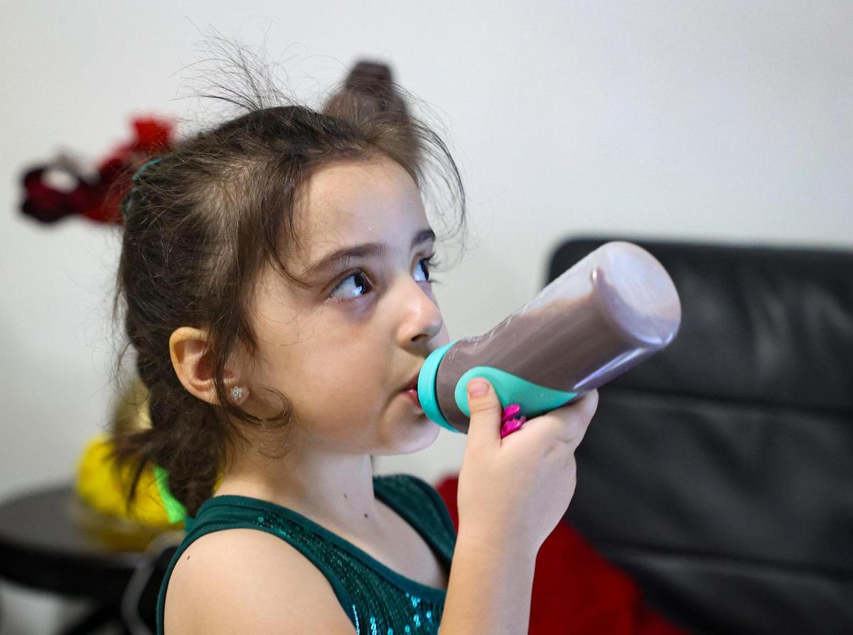 Katherin Leyva, 5, drinks a bottle of milk similar to PediaSure in the family’s apartment on Thursday, Dec. 1, 2022, in Hialeah. Leyva is diagnosed with Autism Spectrum Disorder. The family lost the majority of their possessions in a fire.