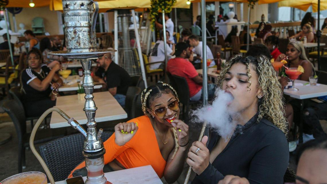 Spring breakers Karsyn Mcleod, 21, and Zayasha Fowler, 21, sit at a hookah bar and lounge on Ocean Drive in South Beach on Thursday, March 12, 2021.
