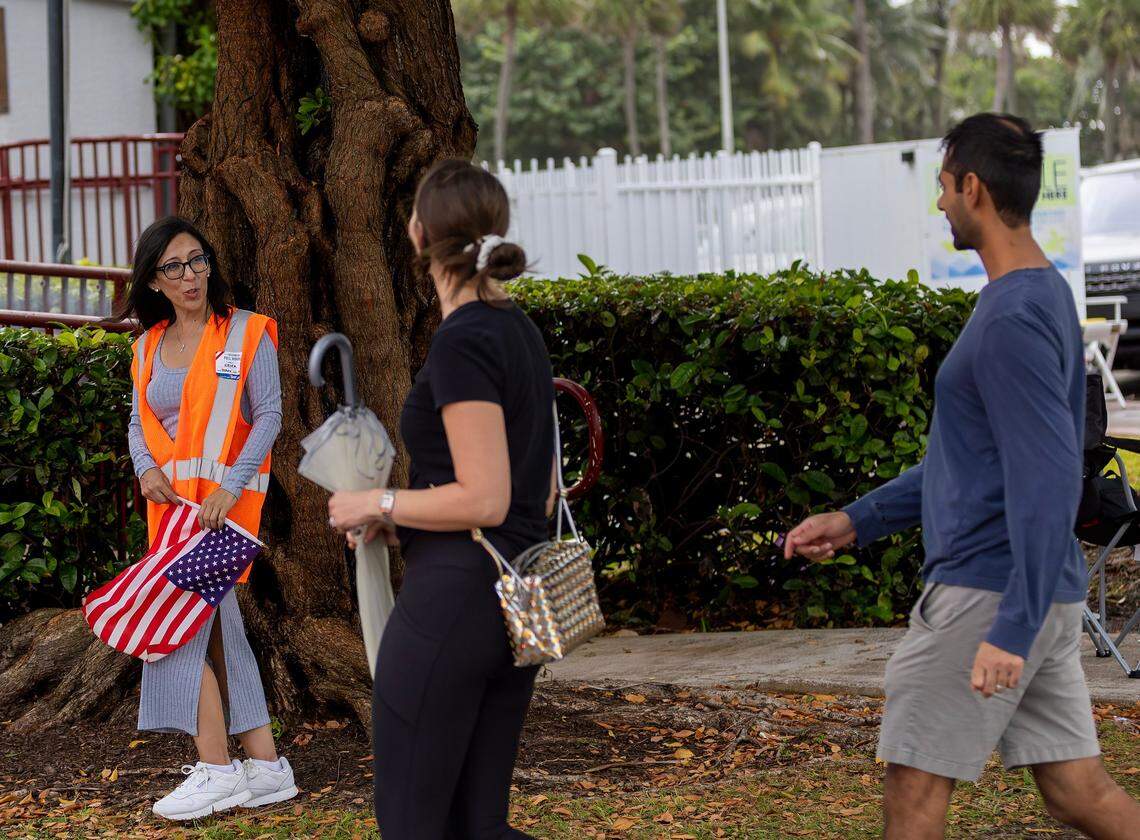 Polling worker Erika Lozano greets voter as their drive to cast their vote during the general Election in Miami-Dade County at the Miami Beach Fire Station #3 on Tuesday, Nov. 5, 2024, in Miami Beach, Fla.