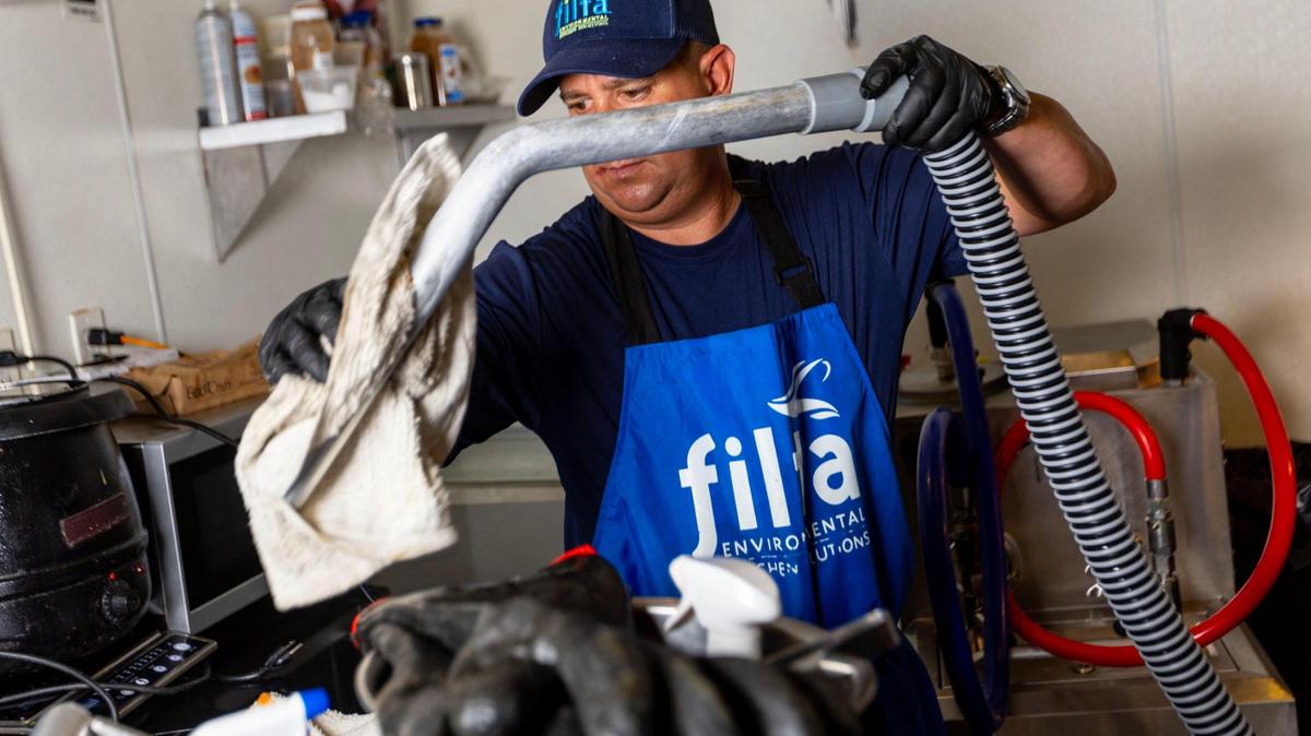 Filta service technician Richard Erin, 42, wipes off the vacuum-based filtration system after cleaning a fryer at Cerveceria La Tropical in the Wynwood section of Miami, on Wednesday, May 24, 2023.