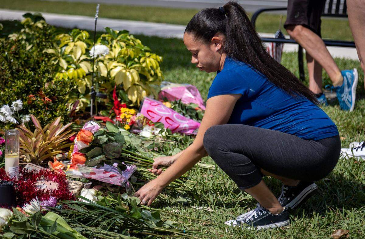 A woman leaves flowers at a memorial at Marjory Stoneman Douglas High School in Parkland, Fla., on Tuesday, Feb. 14, 2023.