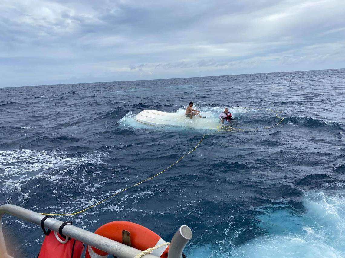 Two men cling to an overturned boat Saturday, July, 18, 2020, off Key Largo. A U.S. Coast Guard crew rescued them.
