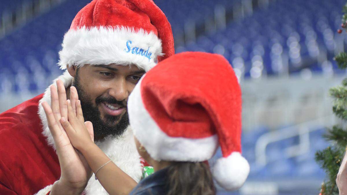 Miami Marlins pitcher Sandy Alcantara, dressed as “Sandy Claus” gives a high five to a student from CNC Learning Enrichment Program at Alpha Charter of Excellence as part of the Marlins’ Holiday Wishes Party on Monday, Dec. 11, 2023, at loanDepot park.