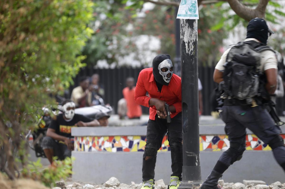 Armed off-duty police officers take cover during an exchange of gunfire with army soldiers during a protest over police pay and working conditions, in Port-au-Prince, Haiti, Sunday, Feb. 23, 2020.
