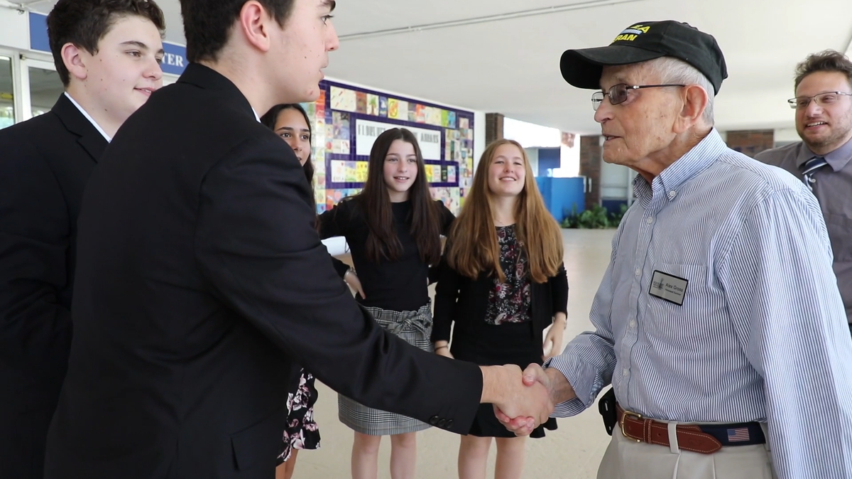 Ben Barnes, a Hebrew Academy eighth grader at the time, shakes hands of Holocaust Survivor Alex Gross when Gross visited the school last year as part of the ‘Names, Not Numbers’ program. From left, students Emanuel Pinkasov, Simone Somek, Hannah Folk and Kayla Herssein and teacher Glenn Katzman.