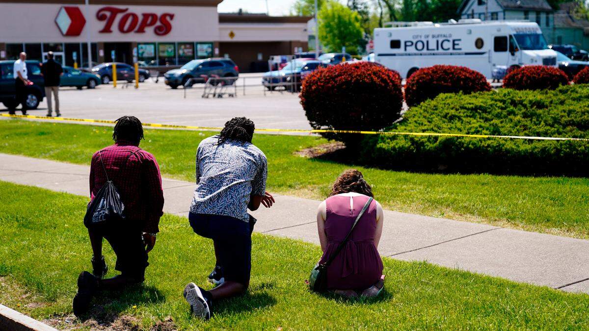 People pray outside the scene of Saturday’s shooting at a supermarket, in Buffalo, N.Y., Sunday, May 15, 2022. The shooting is the latest example of something that’s been part of U.S. history since the beginning: targeted racial violence. (AP Photo/Matt Rourke)