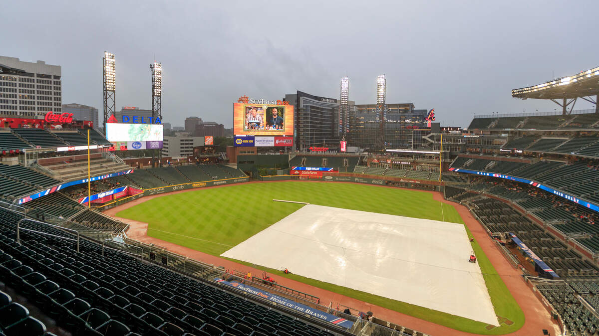A tarp covers the infield during a delay before a baseball game between the Miami Marlins and the Atlanta Braves, Wednesday, Aug. 1, 2018, in Atlanta. (AP Photo/Todd Kirkland)