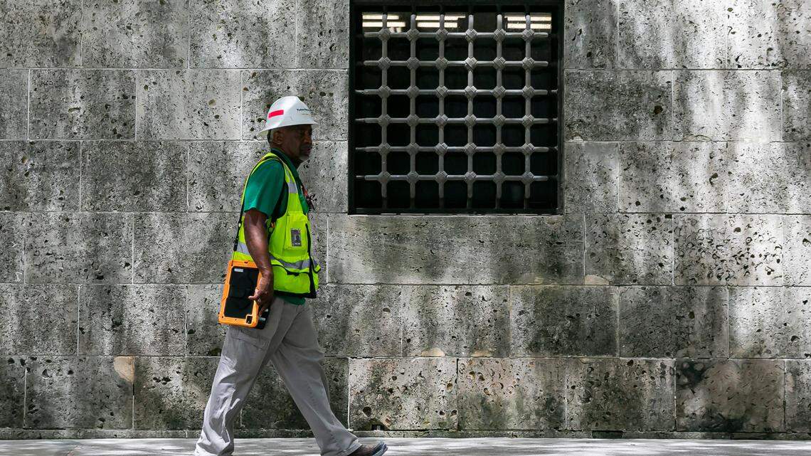 A construction worker walks on Flagler Street past a grated window on the fortress-like base of the Miami-Dade Cultural Center downtown.