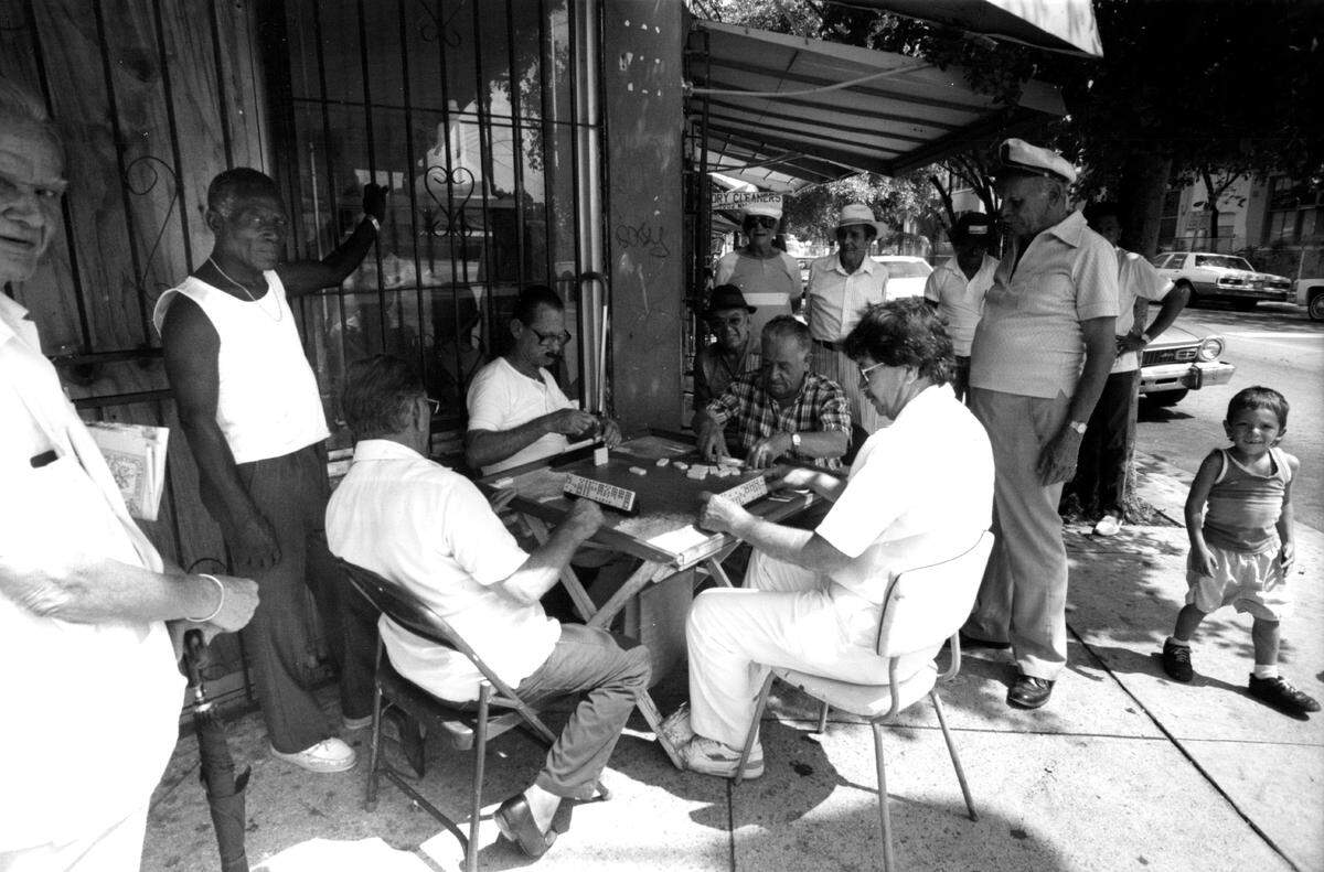 A group of neighbors in Wynwood play dominoes in a corner on Second Avenue.