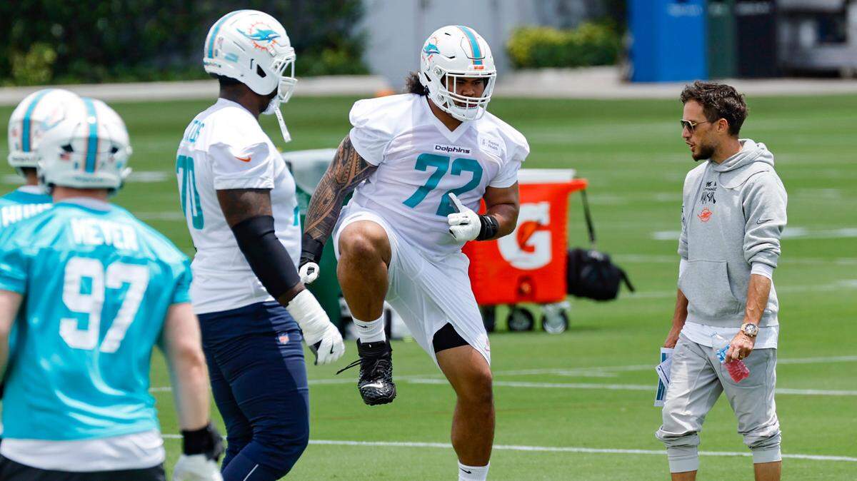 Miami Dolphins offensive lineman Jonah Savaiinaea (72) runs through drills as coach Mike McDaniel watches during Dolphins rookie minicamp at the Baptist Health Training Complex in Miami Gardens, Florida on Friday, May 9, 2025.
