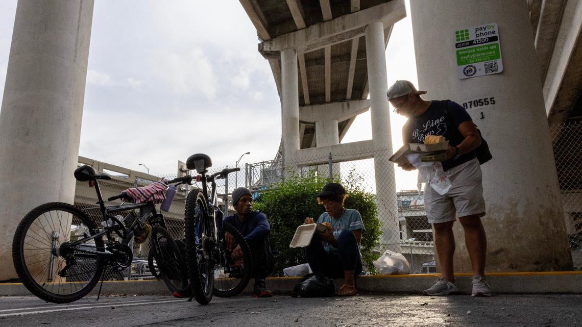 Ileana Napoleoni, center, sits with some friends as she eats a free meal provided by the nonprofit One World One Heart on Thursday, Sept. 12, 2024, in Miami.