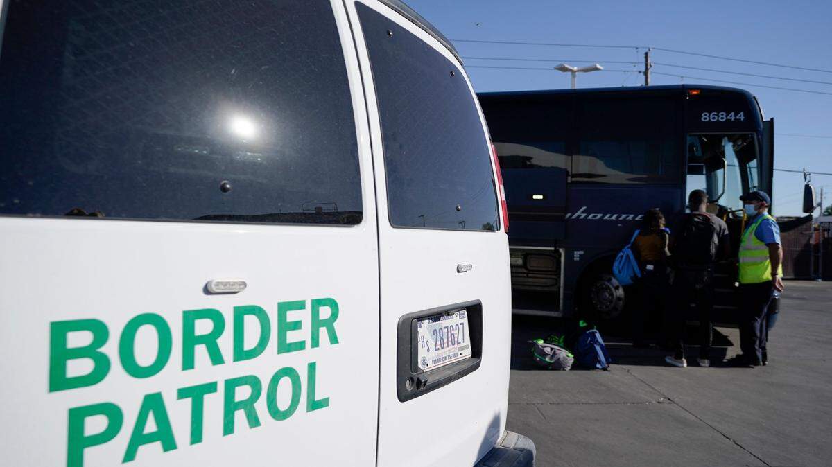 A U.S. Customs and Border Protection van is seen next to a bus picking up travelers, mostly migrants from Haiti released from CBP custody, at a gas station that serves as a bus terminal, on Sept. 23, 2021, in Del Rio, Texas. On Dec. 25, one person was killed and three were injured after Border Patrol agents pursued their vehicle in San Diego, California.