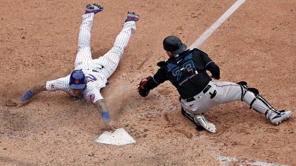 New York Mets’ Javier Baez scores the game winning run past Miami Marlins catcher Alex Jackson during the ninth inning of the first game of a baseball doubleheader that started April 11 and was suspended because of rain, Tuesday, Aug. 31, 2021, in New York. The Mets won 6-5. (AP Photo/Adam Hunger)