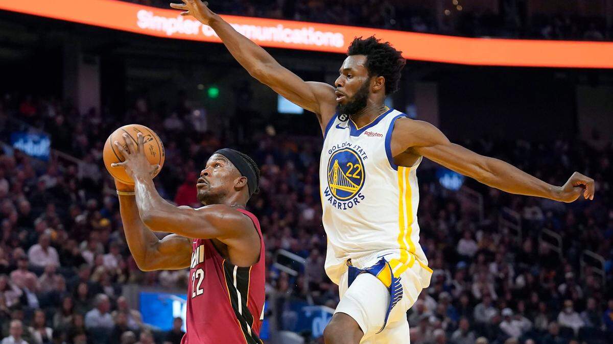 Miami Heat forward Jimmy Butler, left, shoots against Golden State Warriors forward Andrew Wiggins during the first half of an NBA basketball game in San Francisco, Thursday, Oct. 27, 2022.