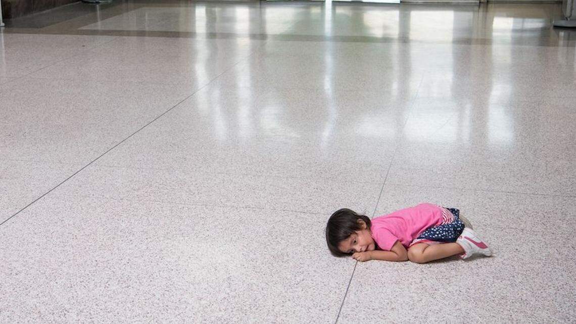 A young migrant girl waits on the floor as her father, released from federal detention with other Central American asylum seekers, gets a bus ticket in McAllen, Texas.