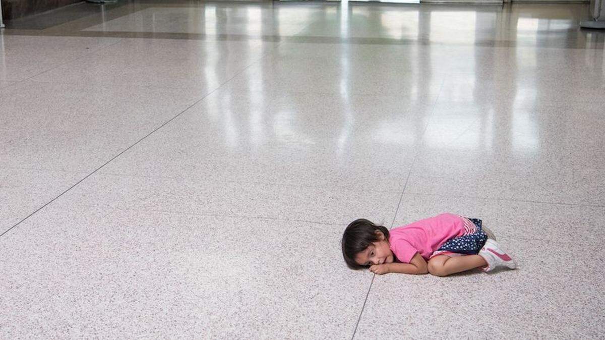 A young migrant girl waits on the floor as her father, released from federal detention with other Central American asylum seekers, gets a bus ticket in McAllen, Texas.