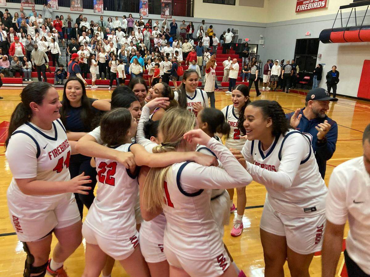 Doral Academy girls’ basketball players celebrate on the court after their win over Boca Raton in the Region 4-7A final at the Doral gym on Thursday, Feb. 22, 2024.