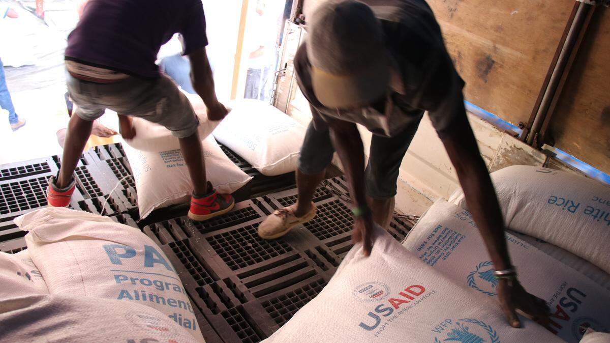 Workers off-load food assistance from trucks at the Chansolme School in northwest Haiti, where the World Food Program set up a general food distribution point.