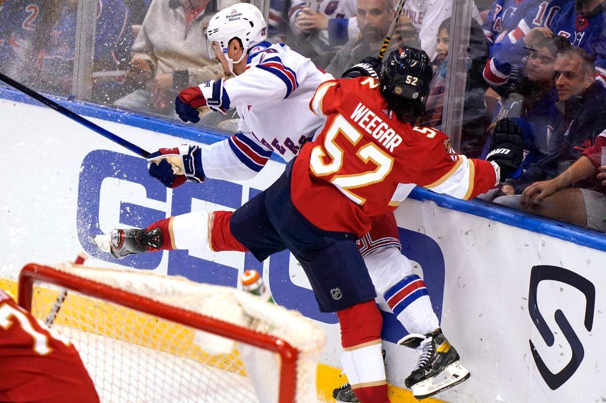 New York Rangers left wing Chris Kreider, left, is checked by Florida Panthers defenseman MacKenzie Weegar (52) during the third period of an NHL hockey game, Wednesday, Dec. 29, 2021, in Sunrise, Fla. The Panthers won 4-3. (AP Photo/Lynne Sladky)