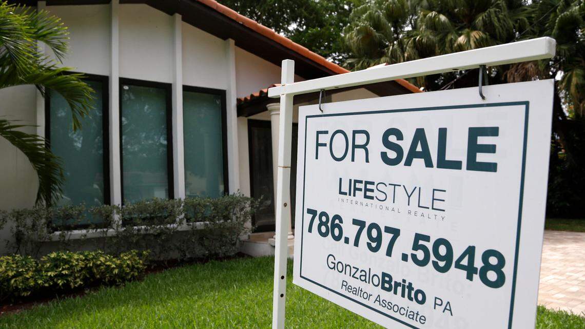 Real estate experts disagree on whether national housing prices will fall in the months ahead. A sale sign hangs in front of a house in Miami in 2015.