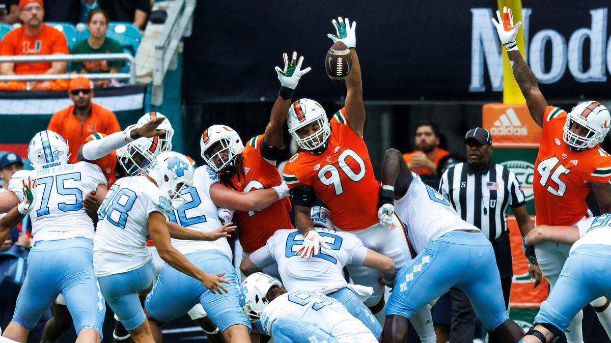 Miami Hurricanes defensive linemans Akheem Mesidor (90) and Jahfari Harvey (12) attempt to block a extra point kick by North Carolina Tar Heels place kicker Noah Burnette (98) during the first quarter of an ACC conference football game at Hard Rock Stadium on Saturday, October 8, 2022 in Miami Gardens, Florida..